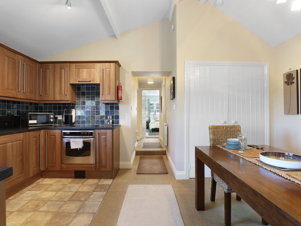A kitchen with wooden cabinets and dining table at Plumtree Cottage in Alnmouth