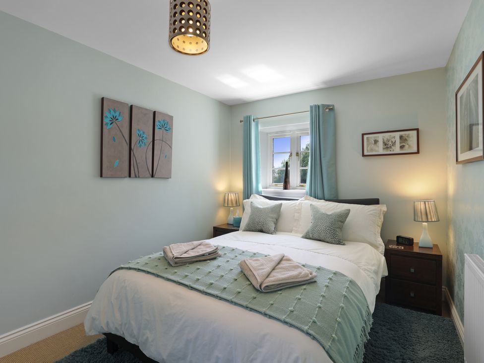 A bedroom with a bed and bedside table at Plumtree Cottage in Alnmouth