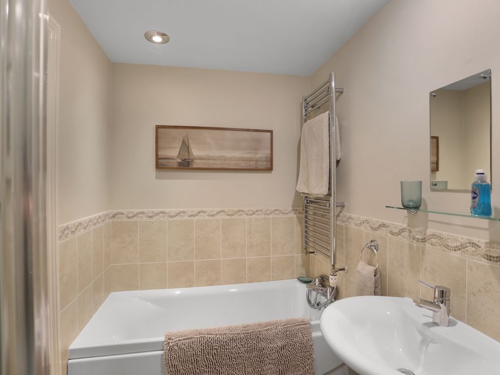 A bathroom with a bathtub and hand basin at Plumtree Cottage in Alnmouth
