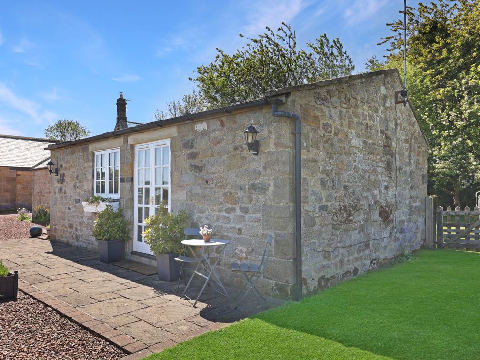 An outdoor patio area with a table and chairs at Plumtree Cottage in Alnmouth