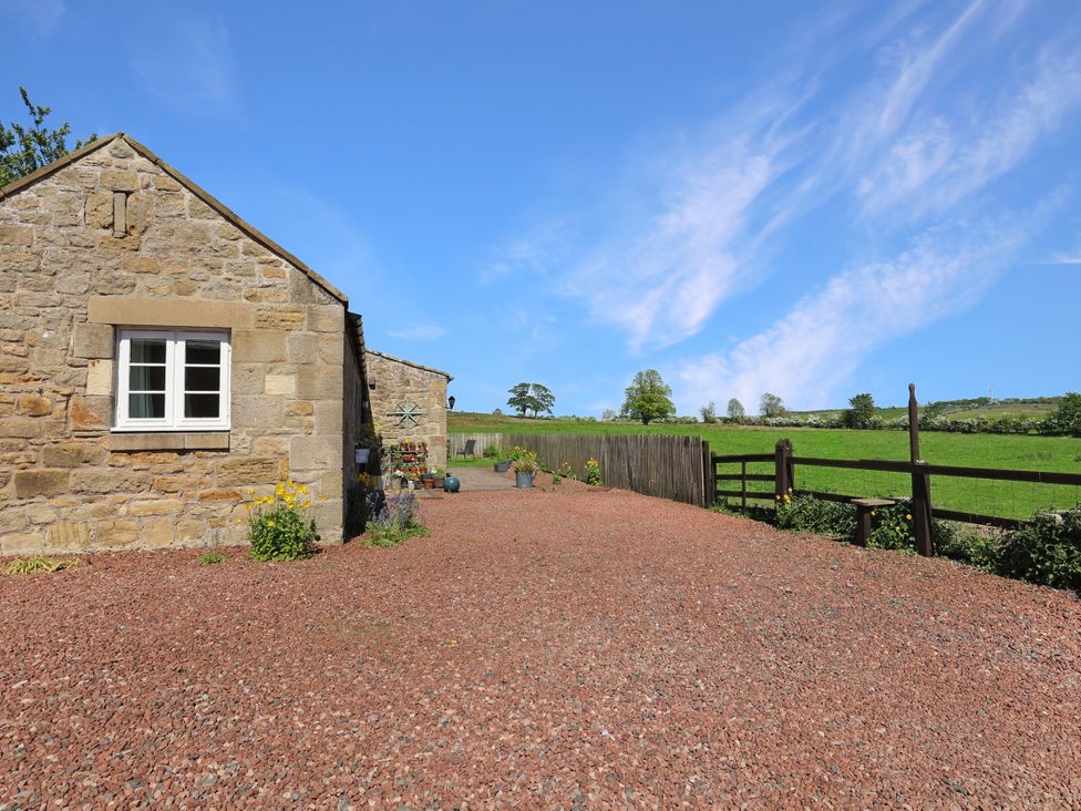 An outdoor area with a stone cottage and gravel driveway at Plumtree Cottage in Alnmouth