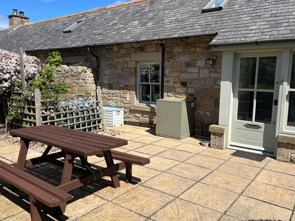 An outdoor area with a wooden table and benches at Beachward in Embleton