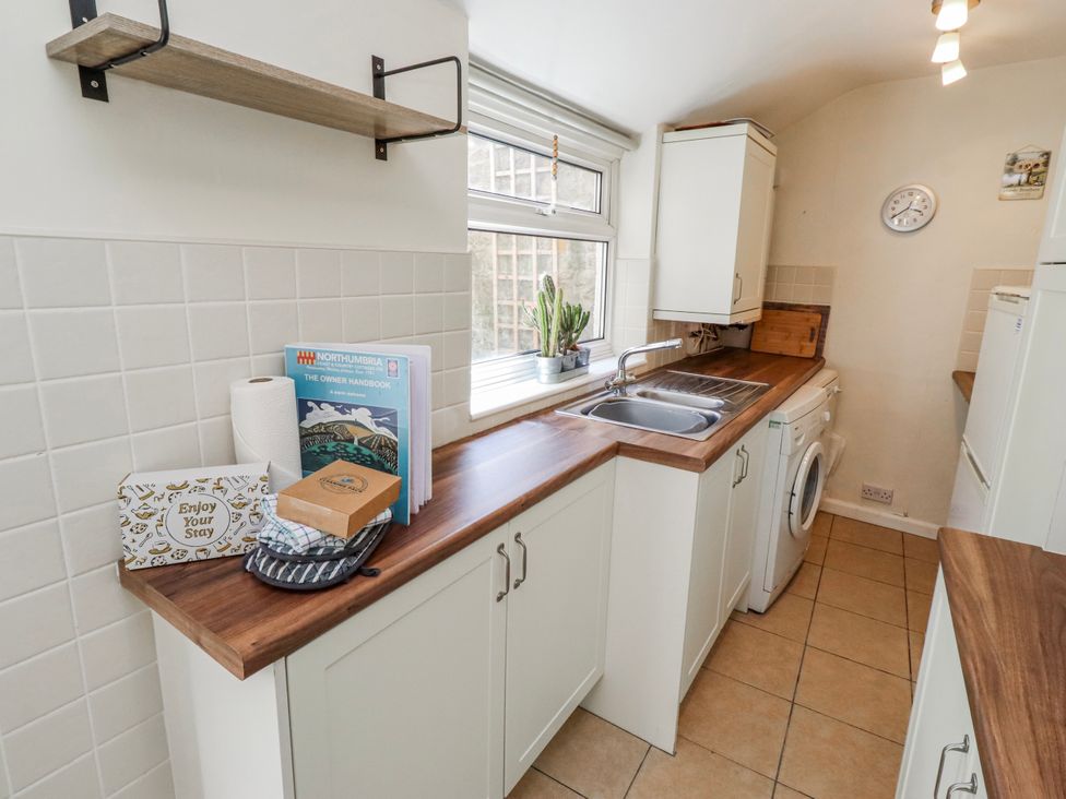 A kitchen with sink, washing machine, and shelves at Hardys House Alnwick