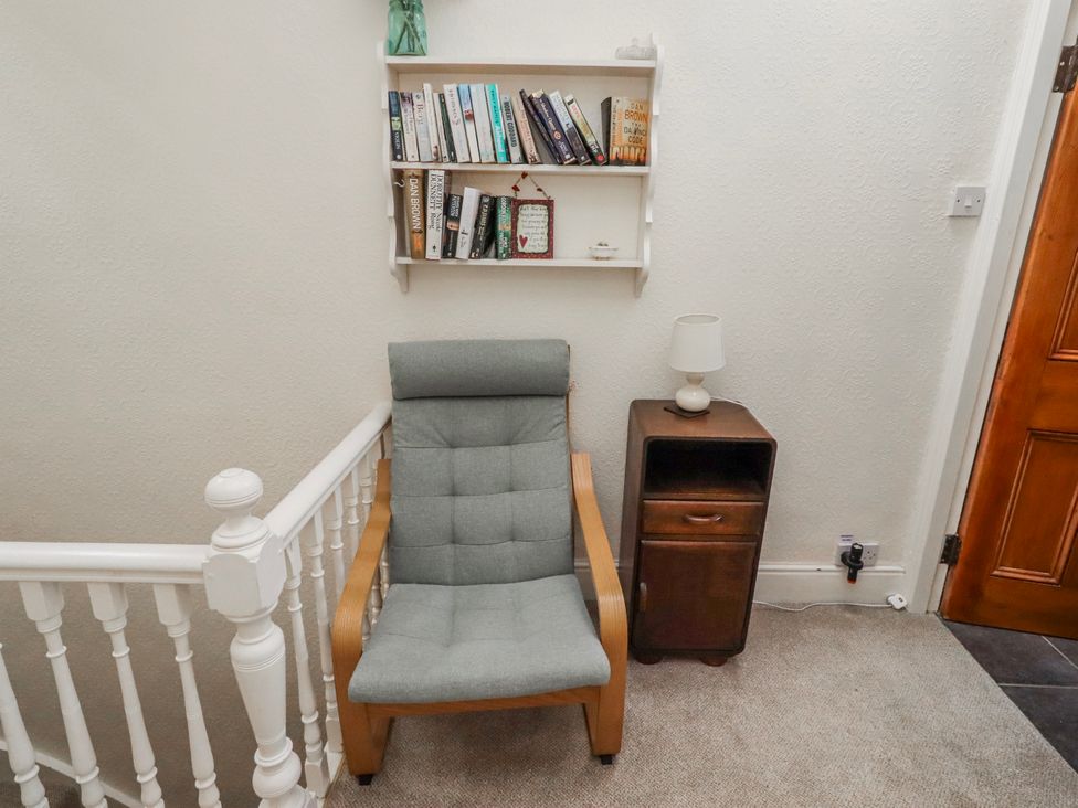A hallway with a chair and bookshelf at Hardys House in Alnwick