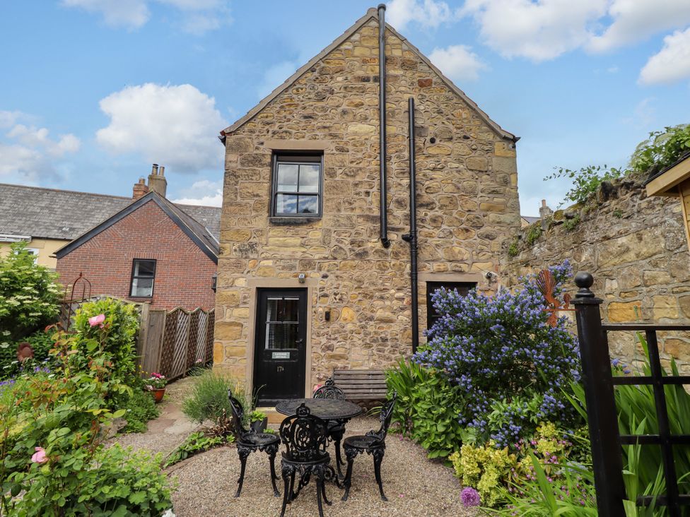 A stone building with a garden and seating area at Lavender Cottage (Bailiffgate) Alnwick
