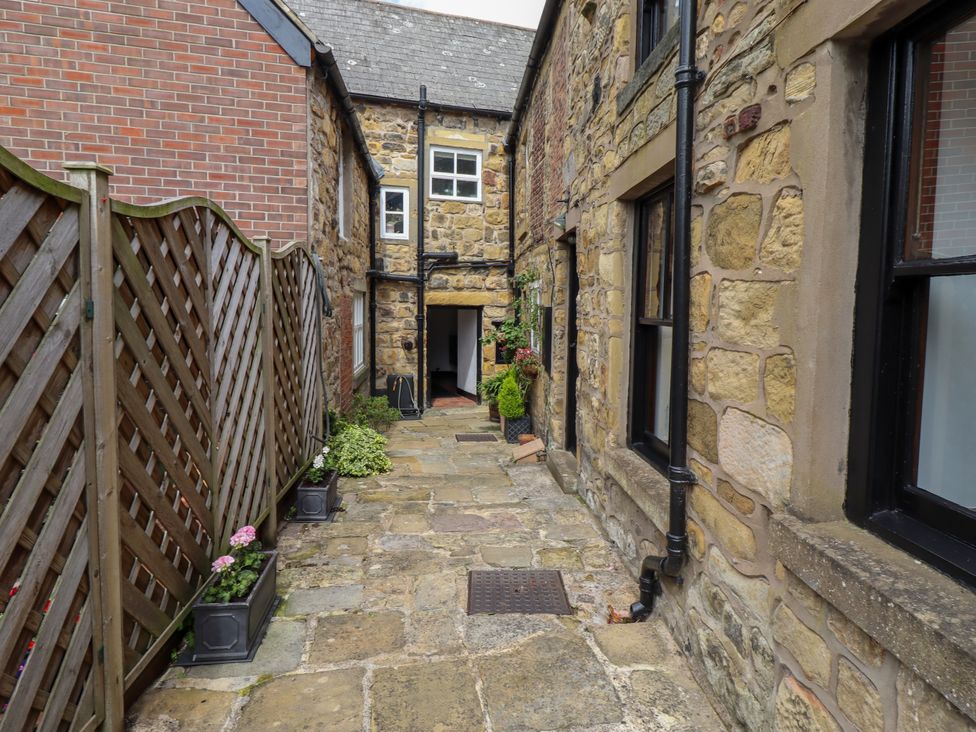 An outdoor corridor with stone walls and planters at Lavender Cottage (Bailiffgate) Alnwick