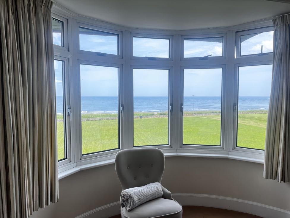 A living room with a bay window view of the ocean at Glenavon in Seahouses