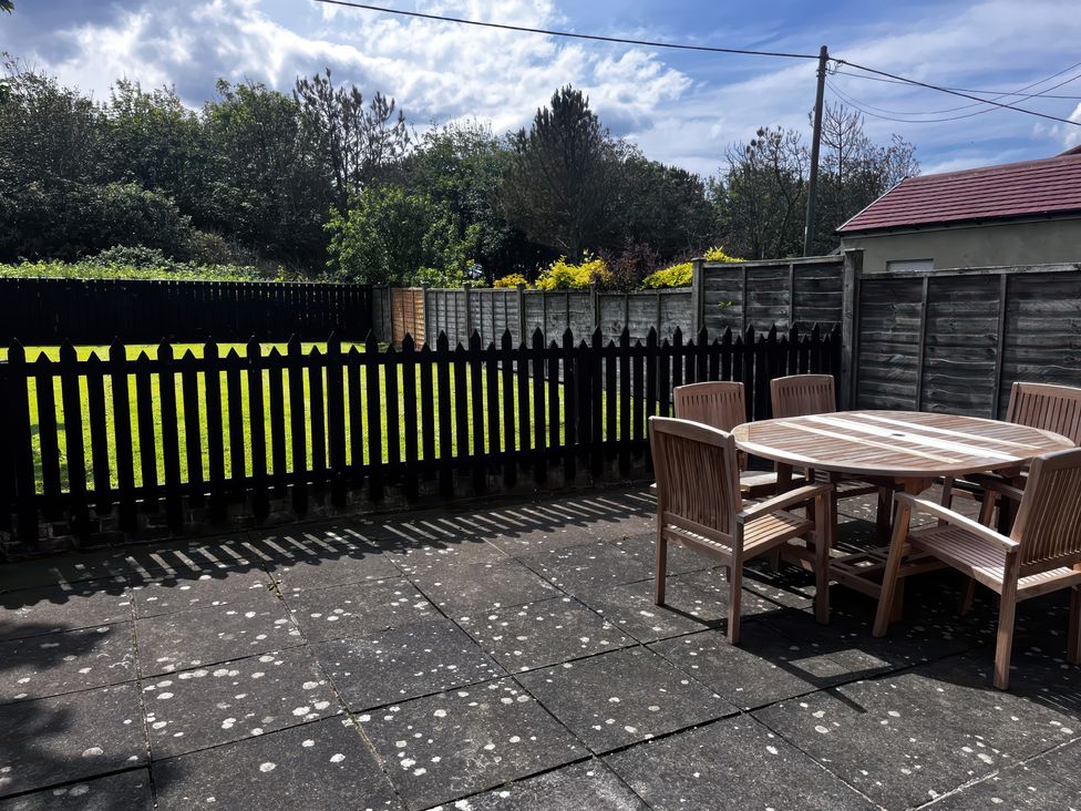 A garden with a wooden table and chairs at Glenavon in Seahouses