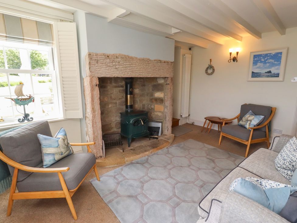 A living room with a fireplace and seating at Marie's Cottage in Craster