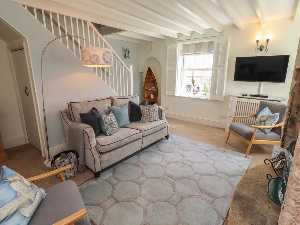 A living room with a sofa and television at Marie's Cottage, Craster