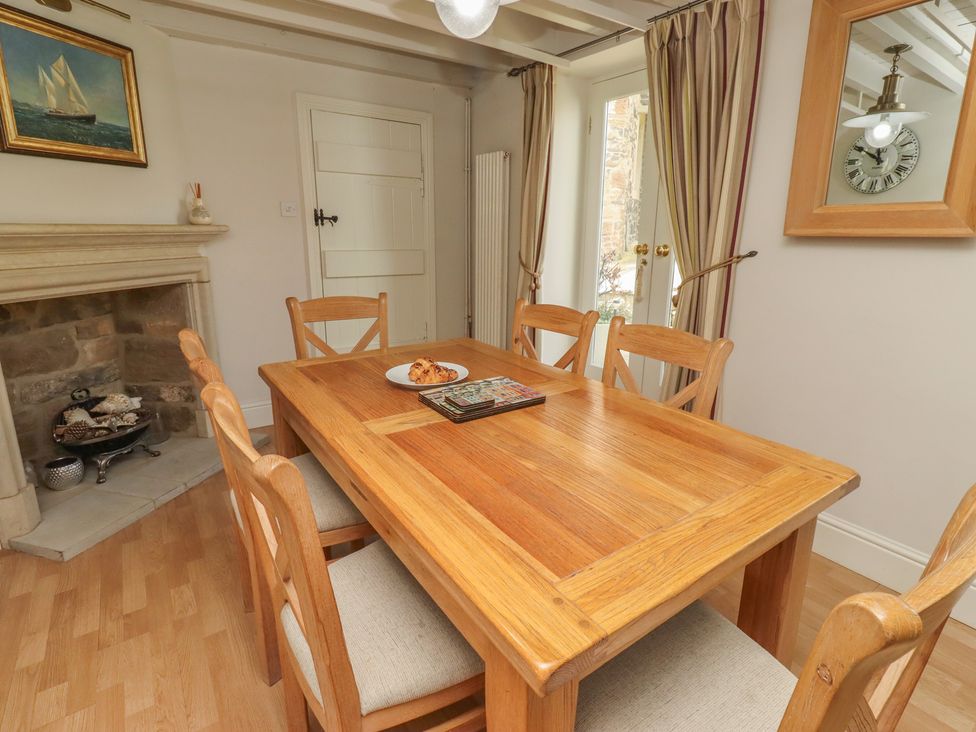 A dining room with a wooden table and chairs at Marie's Cottage in Craster