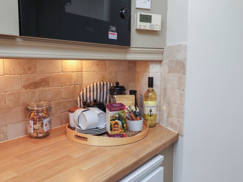 A kitchen with jars and cups on a tray at Marie's Cottage in Craster