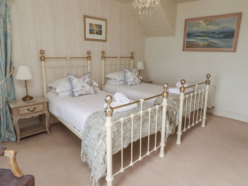 A bedroom with two beds and a nightstand at Marie's Cottage in Craster