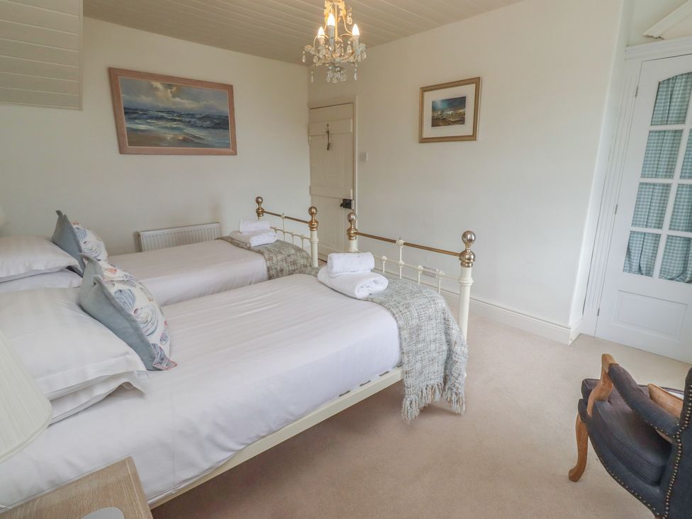 A bedroom with two beds and a chair at Marie's Cottage in Craster