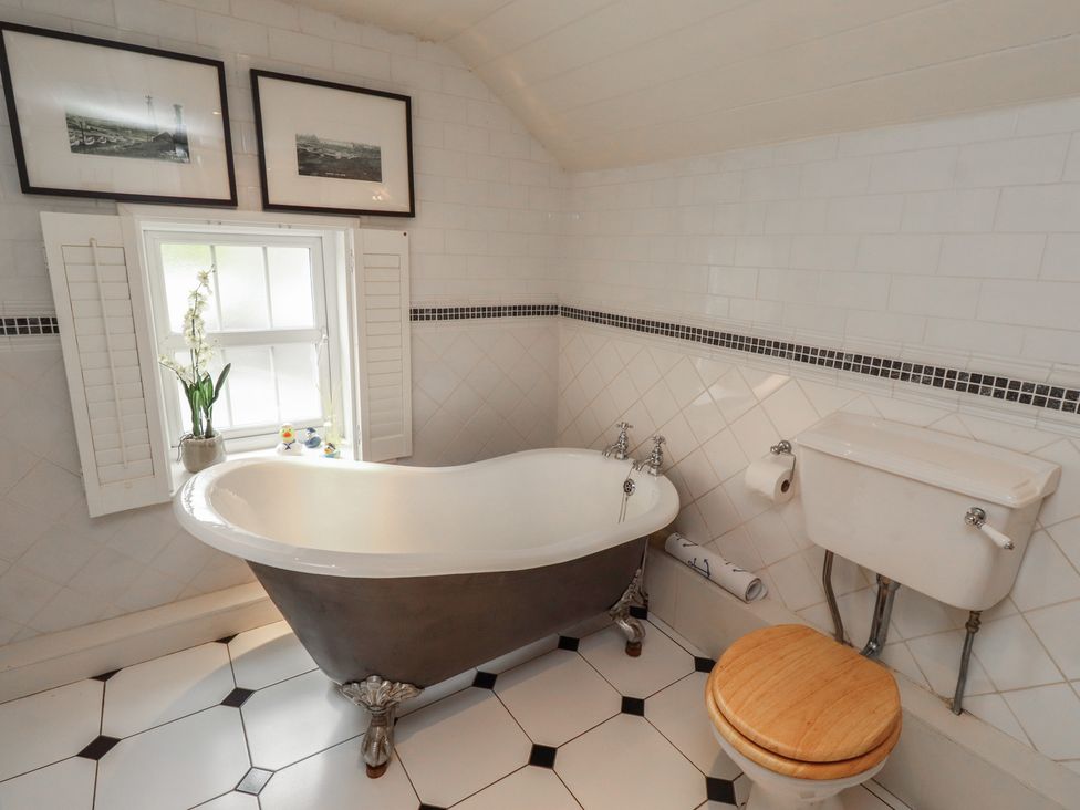 A bathroom with a bathtub and toilet at Marie's Cottage in Craster