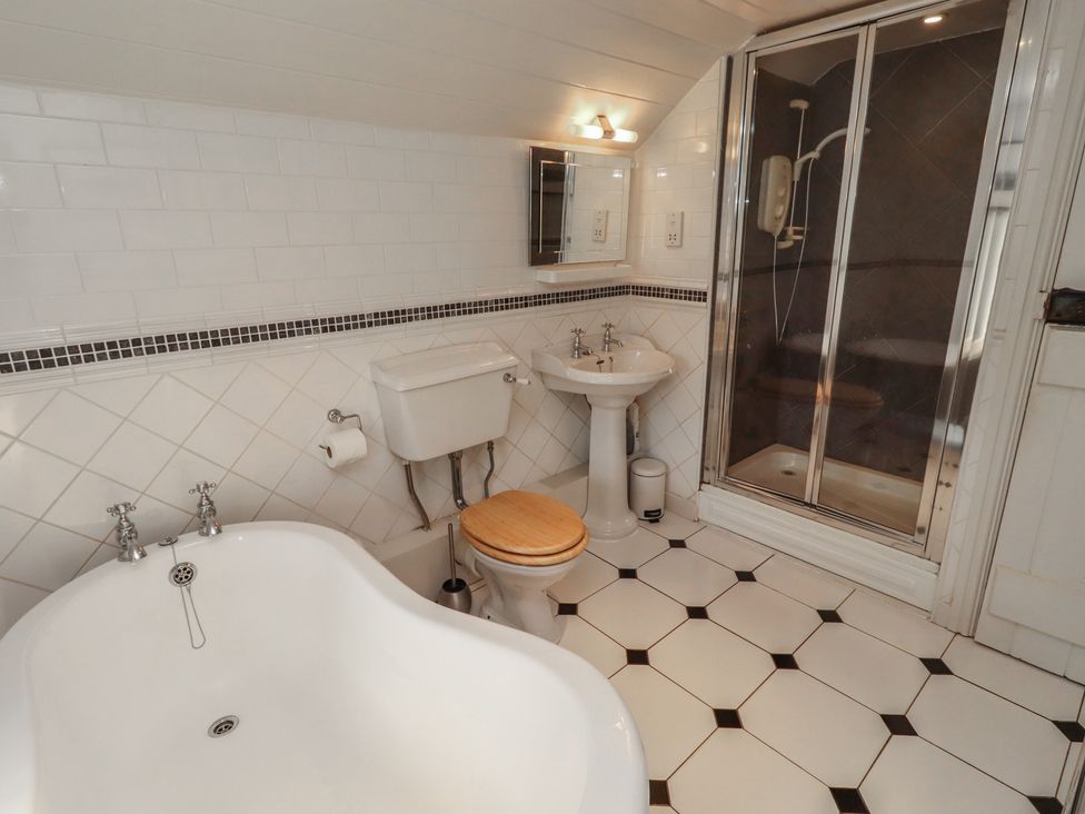A bathroom with a bathtub, toilet, sink, and shower at Marie's Cottage in Craster