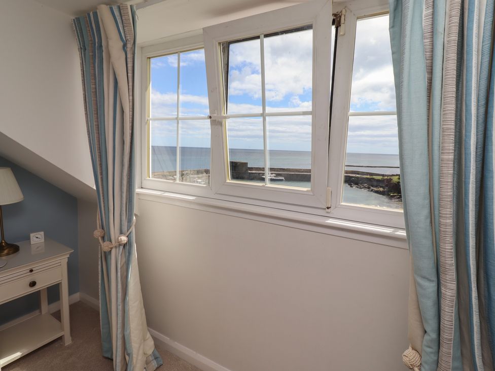 A bedroom with a window overlooking the ocean at Marie's Cottage in Craster