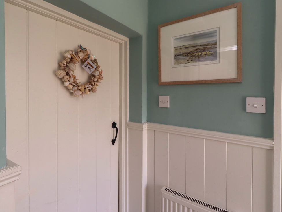 An entrance hall with a door and wreath at Marie's Cottage in Craster