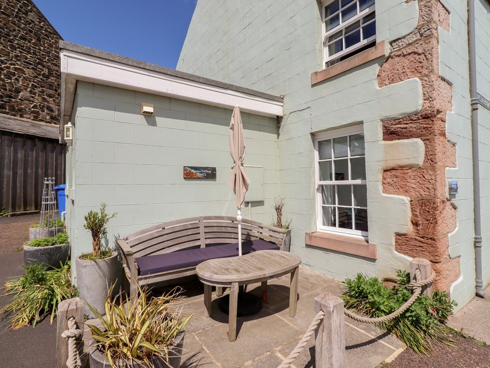 A seating area with a bench and table at Marie's Cottage in Craster