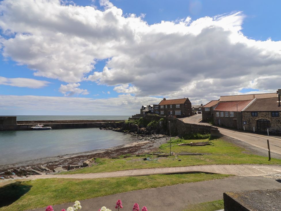 A coastal view with water and buildings at Marie's Cottage in Craster
