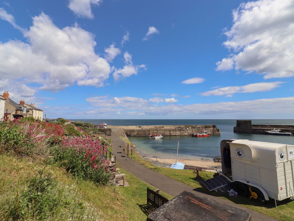 A harbor with boats and houses by the sea at Marie's Cottage in Craster