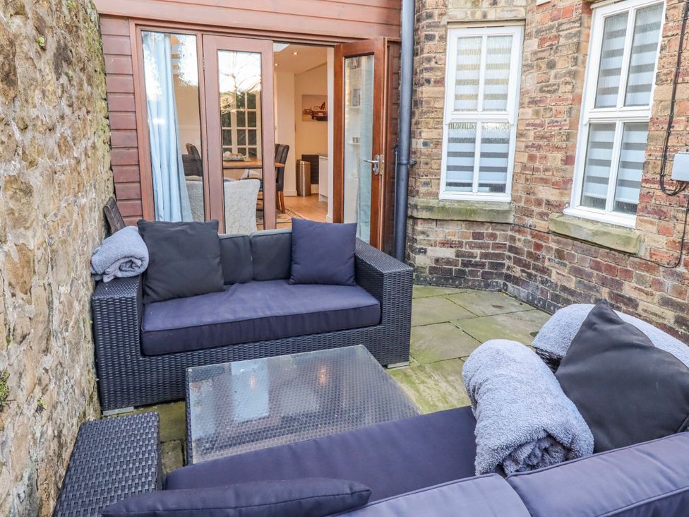 An outdoor patio with a seating area and a glass door at Alnbank in Alnmouth