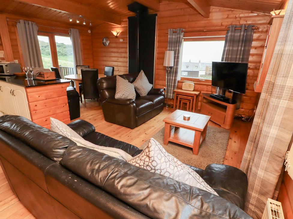 A living room with a sofa and a TV at Heather Cottages - Brown Owl in Bamburgh