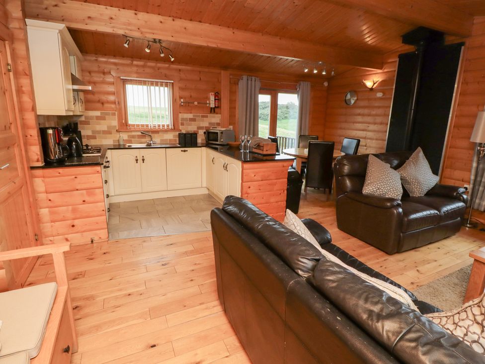 A kitchen and living area with wooden flooring at Heather Cottages - Brown Owl Bamburgh