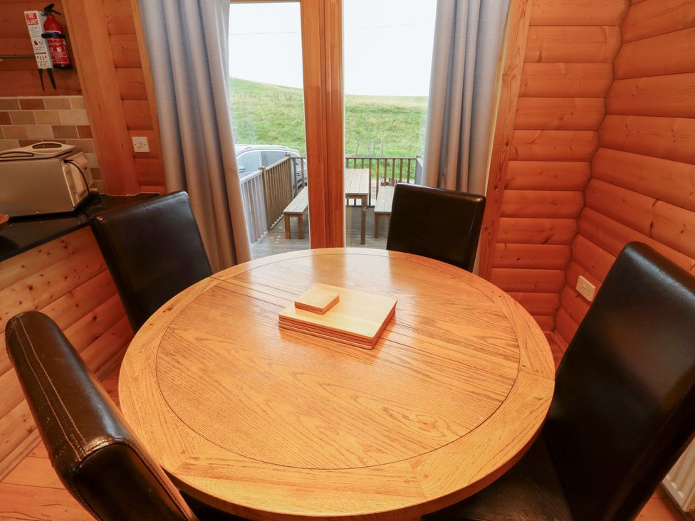 A dining area with a round table and chairs at Heather Cottages - Brown Owl in Bamburgh