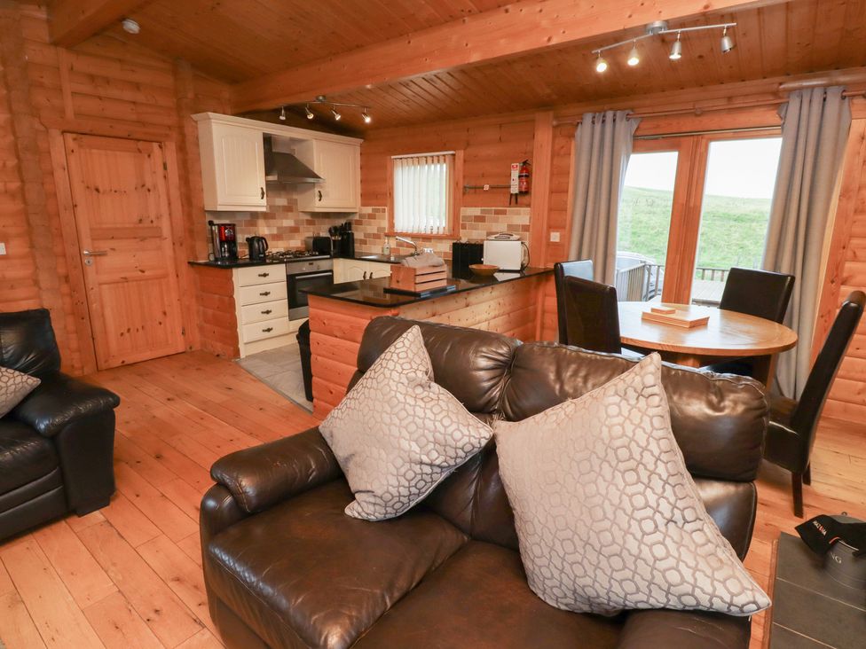 A living room with a sofa and dining area at Heather Cottages - Brown Owl Bamburgh