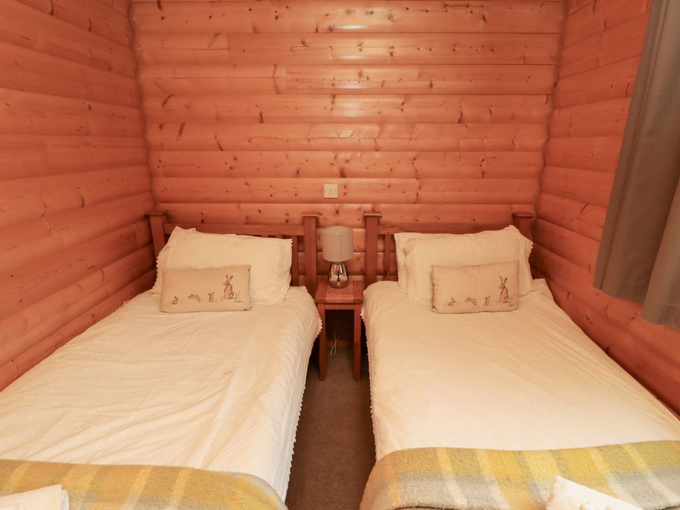 A bedroom with two single beds and a bedside table at Heather Cottages - Brown Owl in Bamburgh