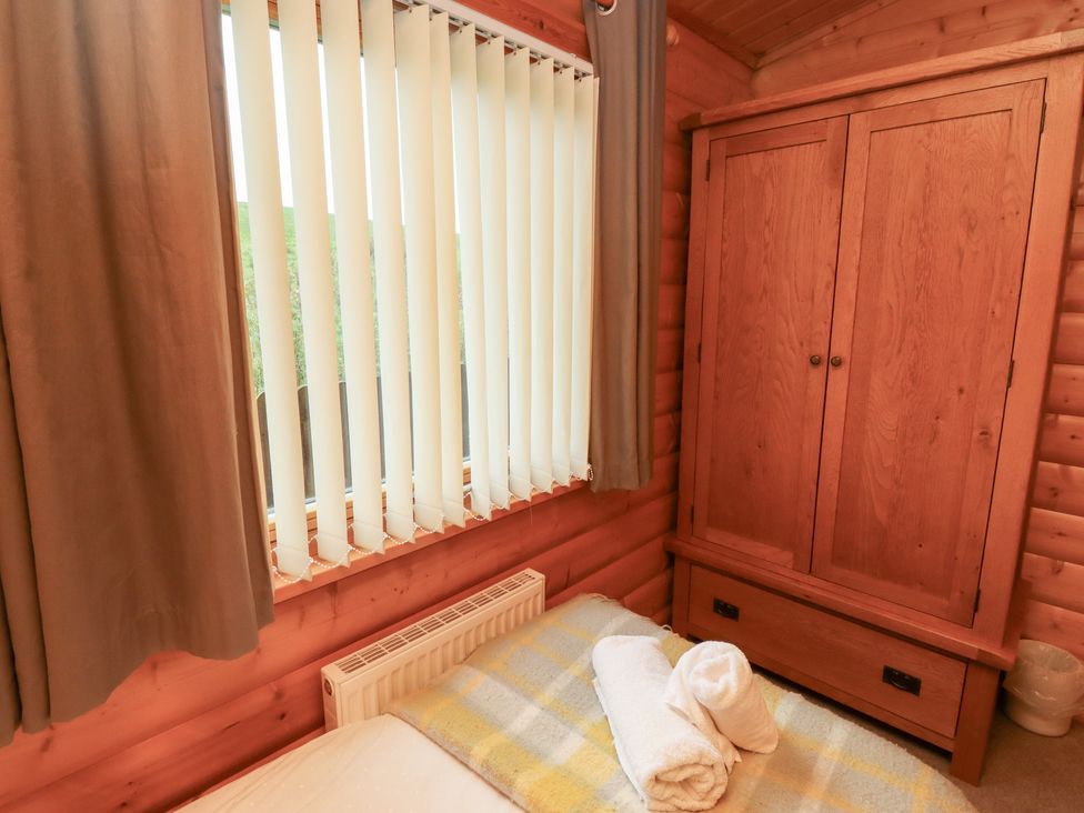 A bedroom with a bed and wardrobe at Heather Cottages - Brown Owl Bamburgh