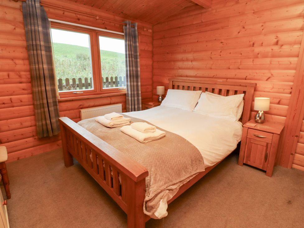 A bedroom with a bed and nightstands at Heather Cottages - Brown Owl in Bamburgh