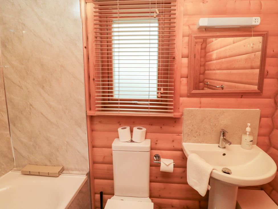 A bathroom with a bathtub, toilet, and sink at Heather Cottages - Brown Owl in Bamburgh