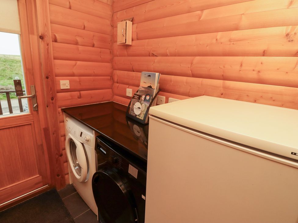 A laundry room with a washing machine and fridge at Heather Cottages - Brown Owl in Bamburgh