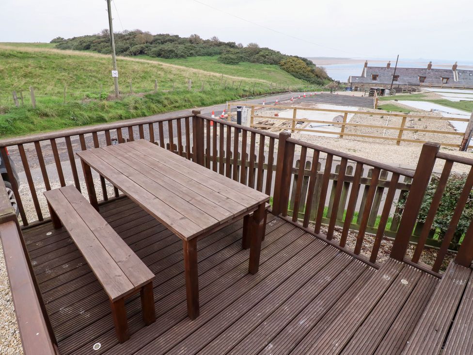 A deck with a wooden table and bench at Heather Cottages - Brown Owl Bamburgh