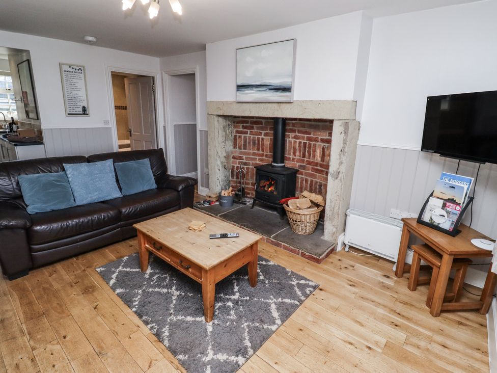 A living room with a fireplace and sofa at Heather Cottages - Godwit in Bamburgh