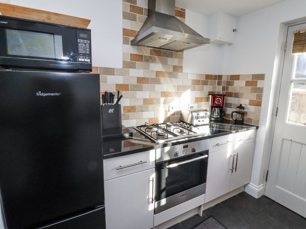 A kitchen with appliances and countertop at Heather Cottages - Godwit in Bamburgh