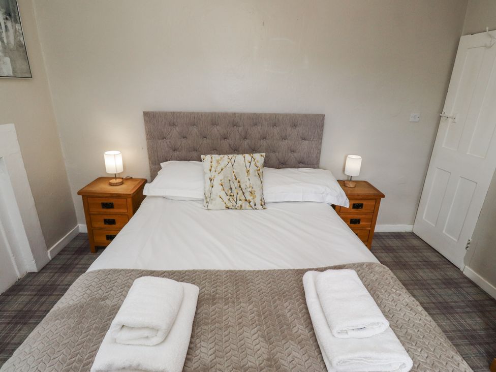 A bedroom with a bed and bedside tables at Heather Cottages - Godwit Bamburgh
