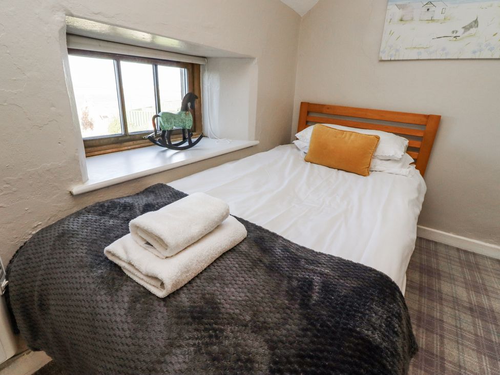 A bedroom with a bed and a window at Heather Cottages - Godwit in Bamburgh