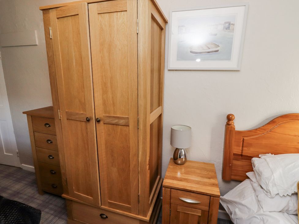 A bedroom with a wardrobe and bedside table at Heather Cottages - Godwit in Bamburgh