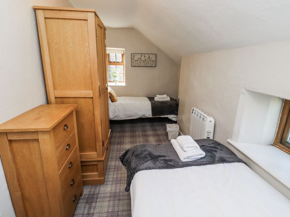 A bedroom with two beds and wooden furniture at Heather Cottages - Godwit in Bamburgh