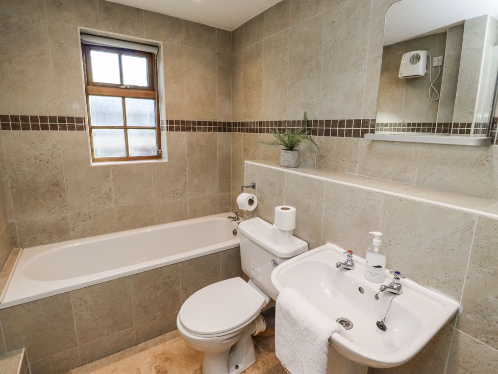 A bathroom with a bathtub, toilet, and sink at Heather Cottages - Godwit in Bamburgh