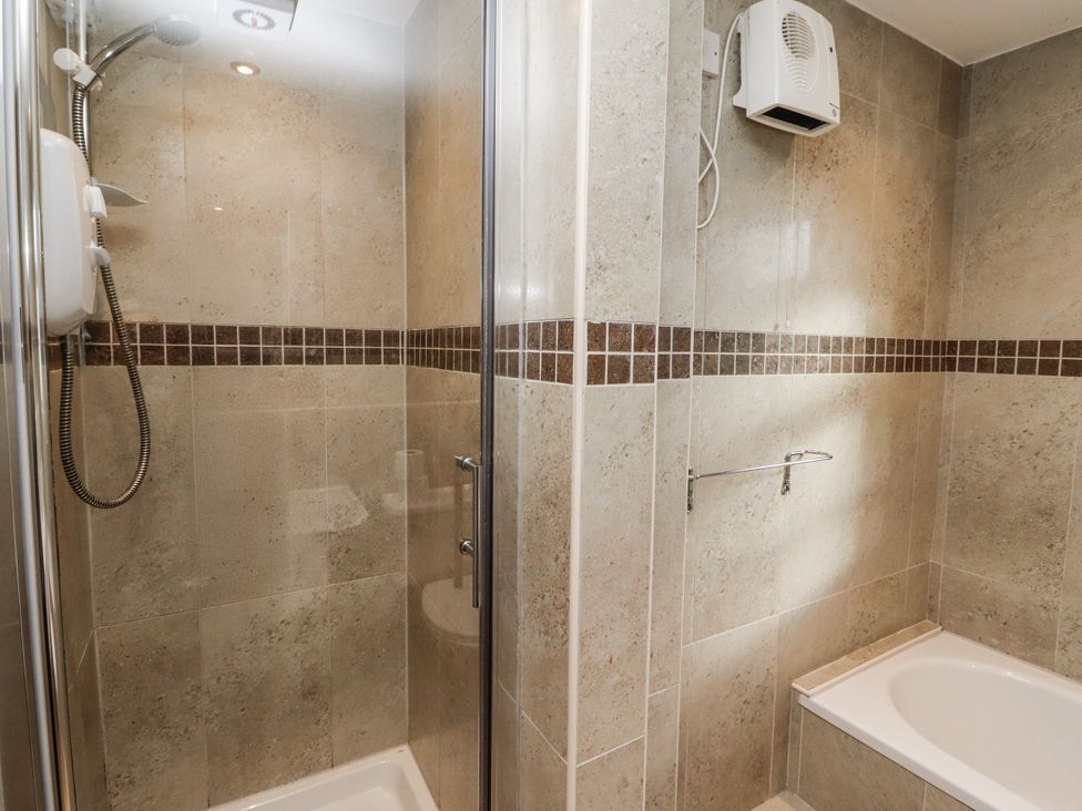 A shower and bath tub in a bathroom at Heather Cottages - Godwit in Bamburgh