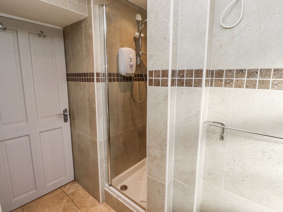 A bathroom with a shower and a door at Heather Cottages - Godwit Bamburgh