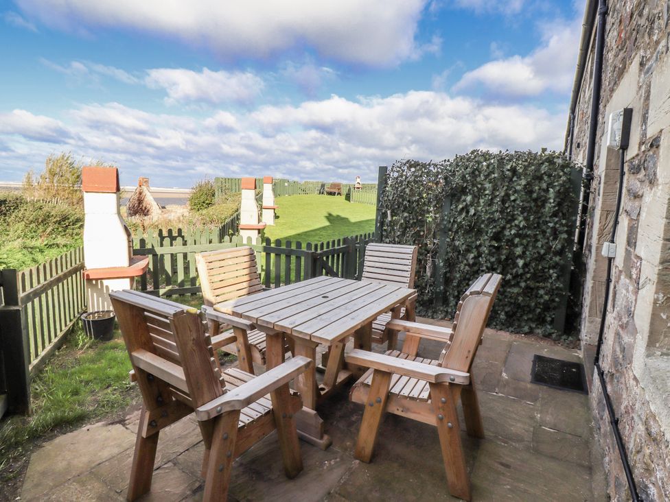 An outdoor seating area with a table and chairs at Heather Cottages - Godwit in Bamburgh