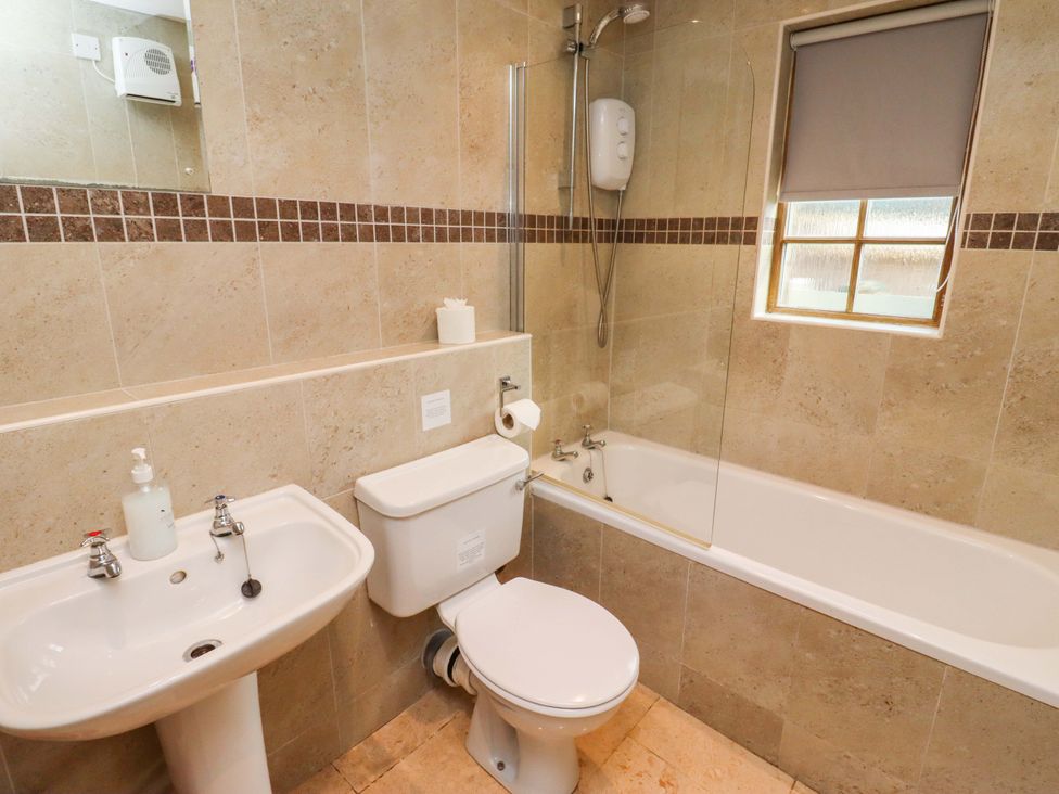 A bathroom with a bath tub, toilet, and sink at Heather Cottages - Grayling in Bamburgh