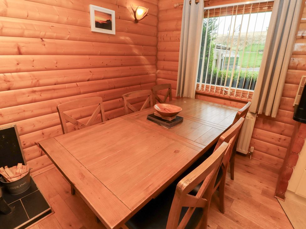 A dining room with a wooden table and six chairs at Heather Cottages - Grey Heron in Bamburgh