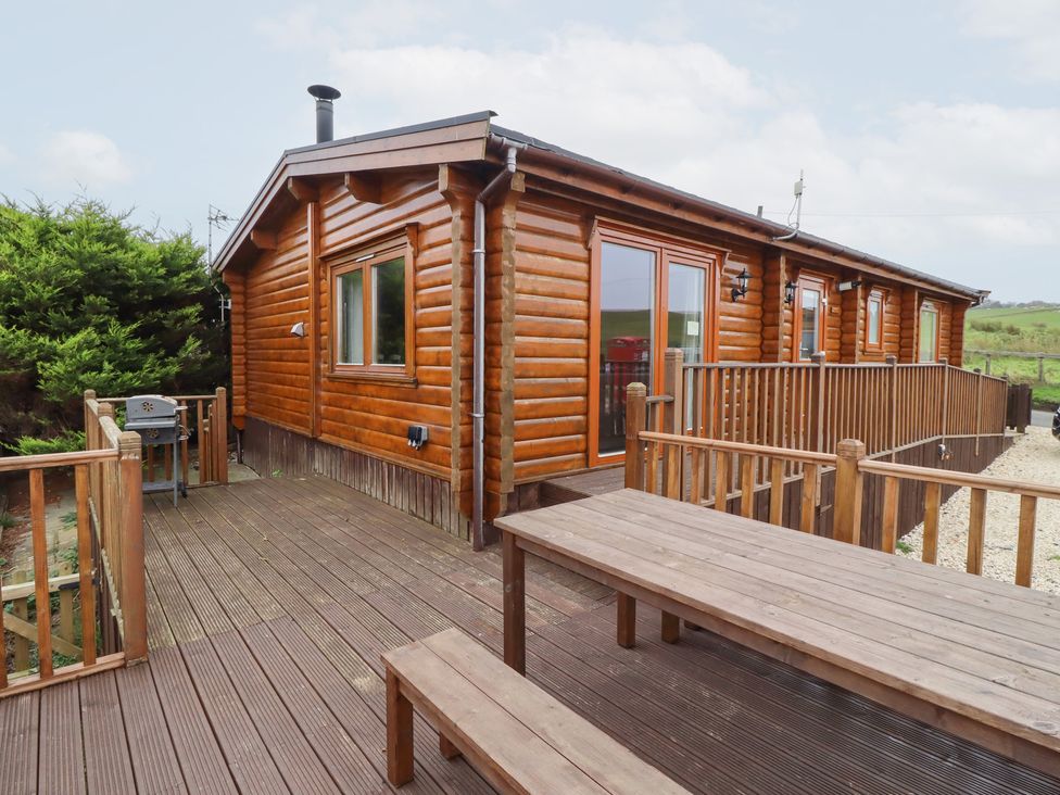 A log cabin with a deck and grill at Heather Cottages - Grey Heron Bamburgh