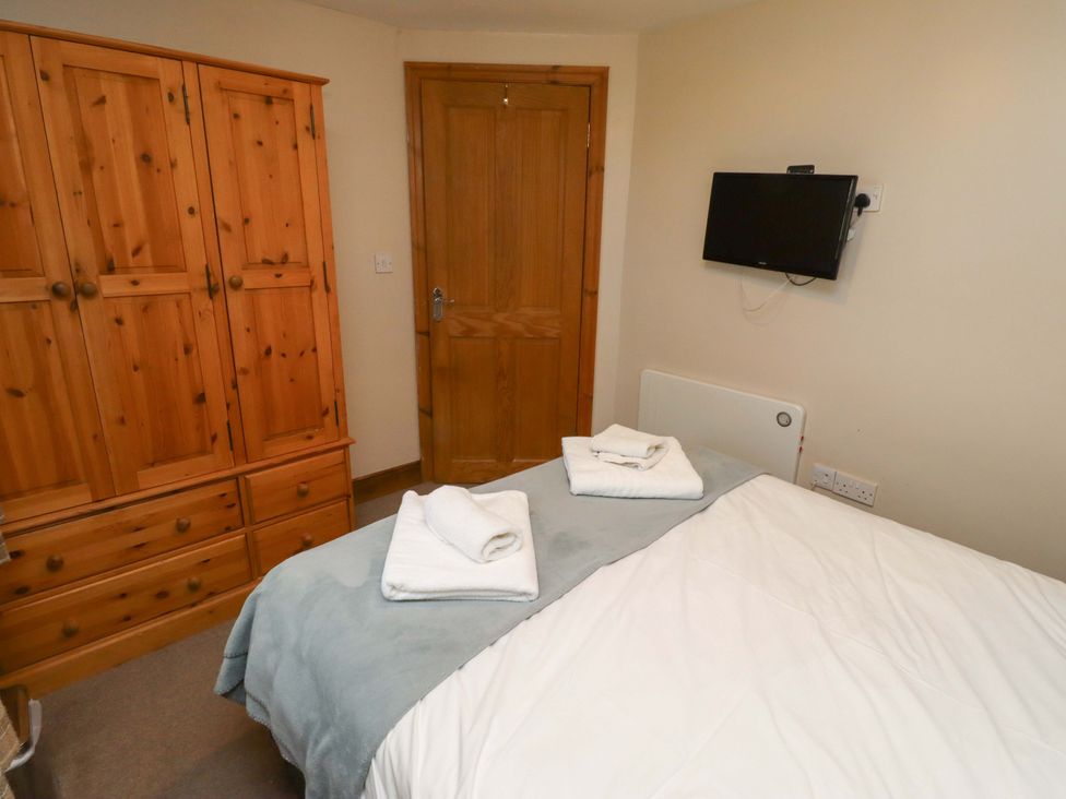 A bedroom with a bed and wardrobe at Heather Cottages - Grey Seal in Bamburgh